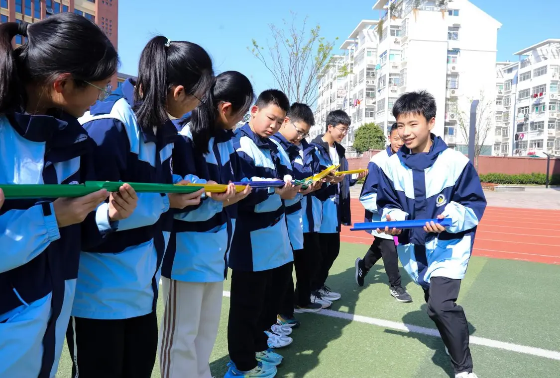 （图为：2025年3月25日，在安徽省合肥市肥西县上派镇安徽师范大学附属肥西第二中学校园内，学生们利用阳光大课间时间在操场上召开“球行万里”心理团辅游戏。）